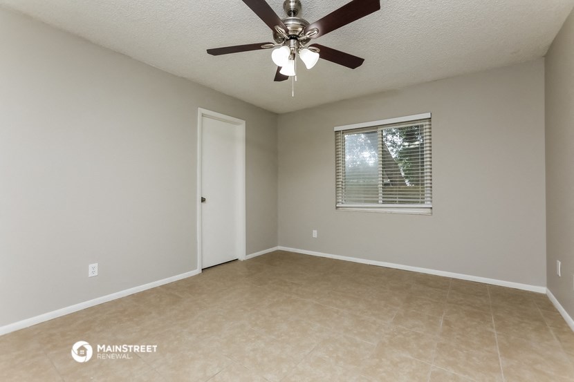 an empty living room with a ceiling fan and a window