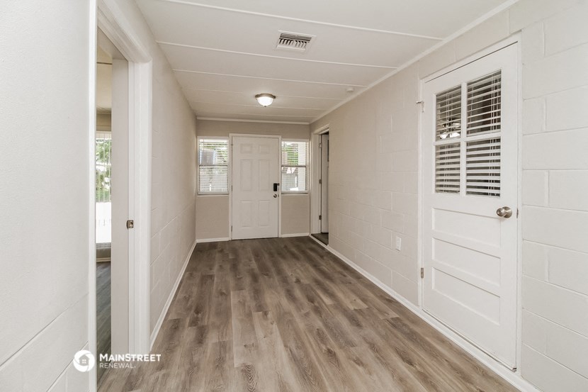 a room with a white door and a hallway with wood flooring