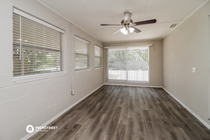 an empty living room with a ceiling fan and windows