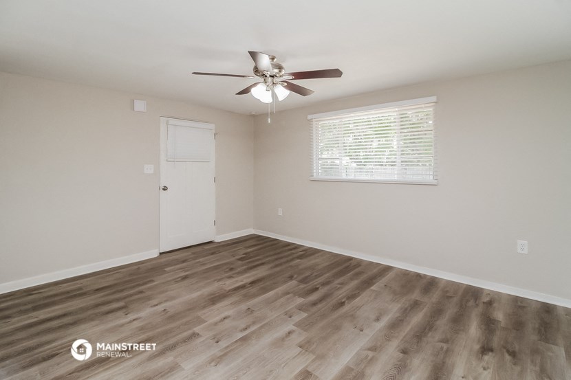 the spacious living room with wood flooring and a ceiling fan