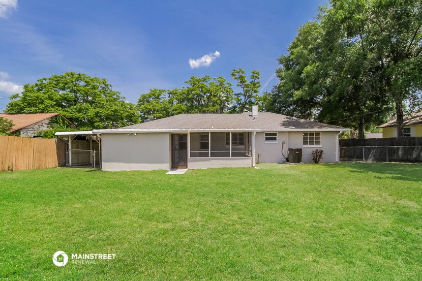 a small white house with a yard and a fence