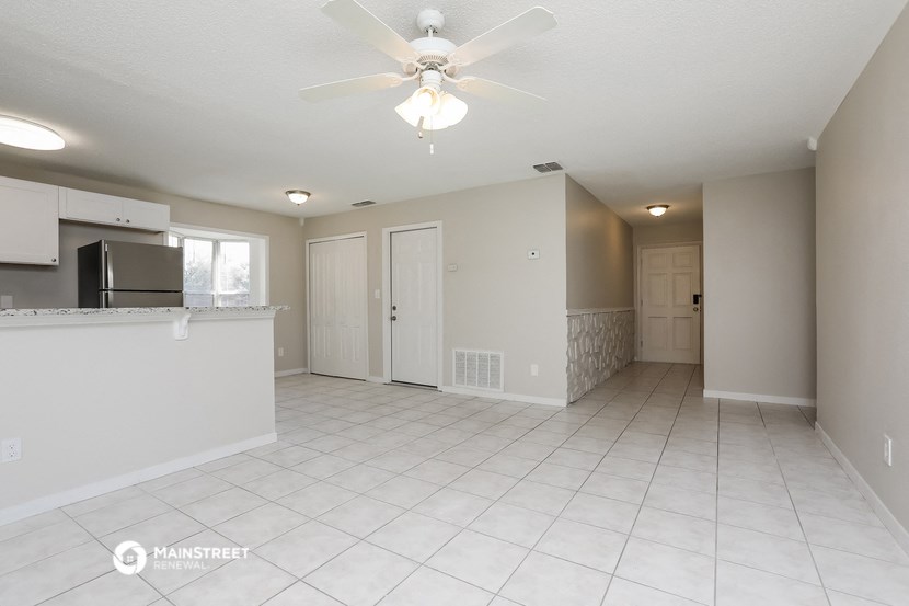 an empty kitchen and living room with a ceiling fan