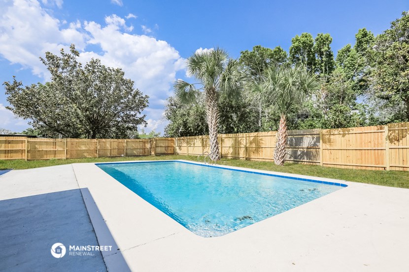 a swimming pool in a backyard with a fence and palm trees