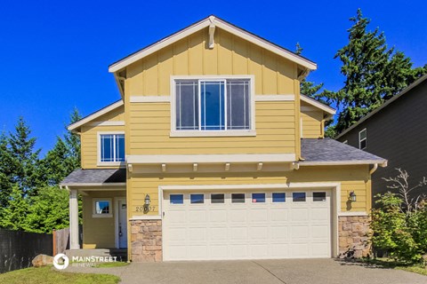 the front of a yellow house with a white garage door