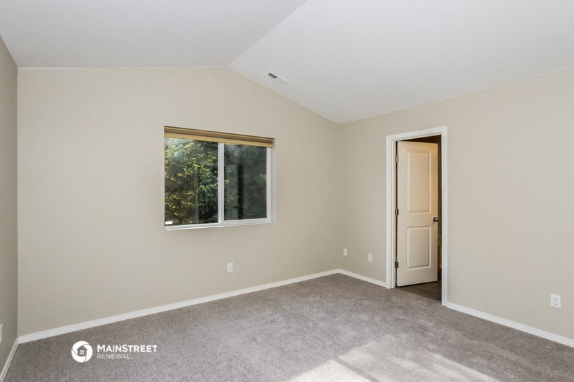 the spacious living room of a manufactured home with carpet and a window