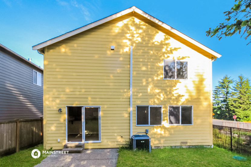 the back of a yellow house with the sun shining on it