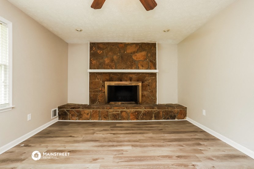 a living room with a stone fireplace and wooden floors