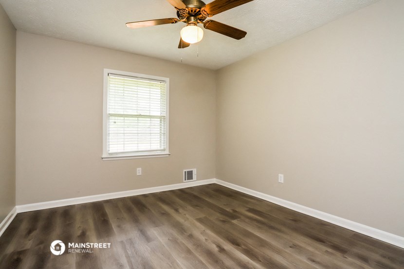 the spacious living room with hardwood floors and a ceiling fan