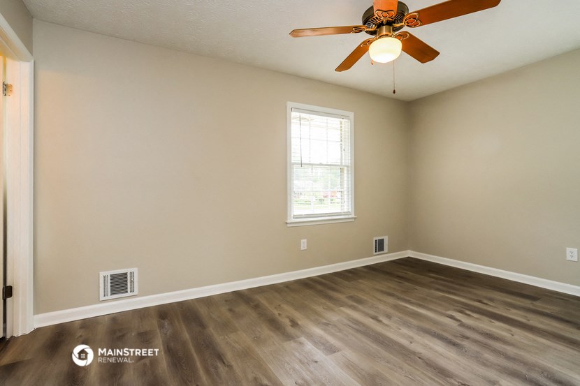 the spacious living room with hardwood floors and a ceiling fan