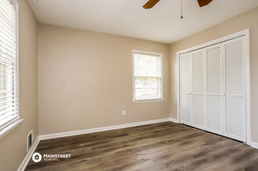 the spacious living room with a closet and a ceiling fan
