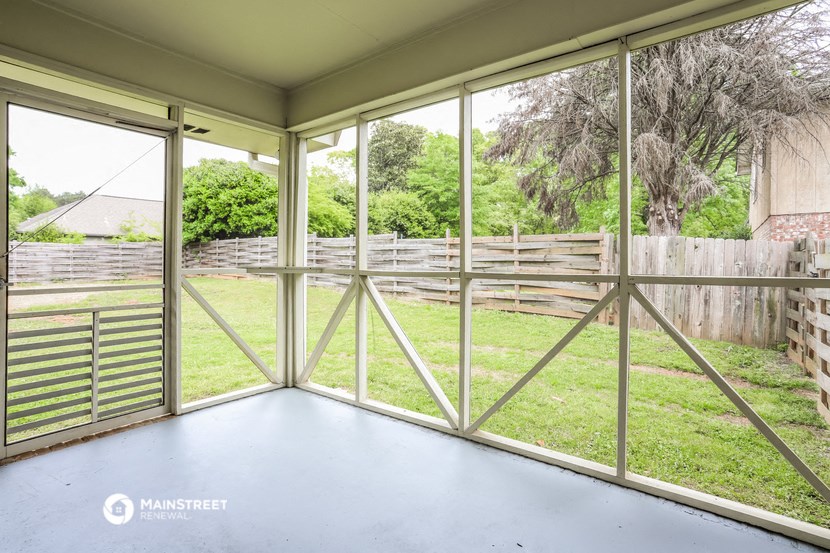 a screened in porch with glass doors overlooking a yard