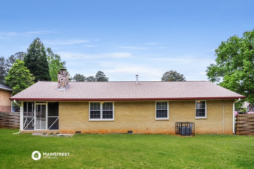 a yellow brick house with a red roof on a green lawn