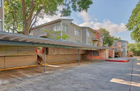 A parking lot in front of a building with a red awning.