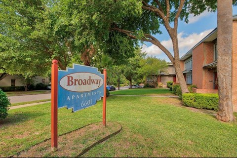 A sign for Broadway Apartments stands in front of a building.