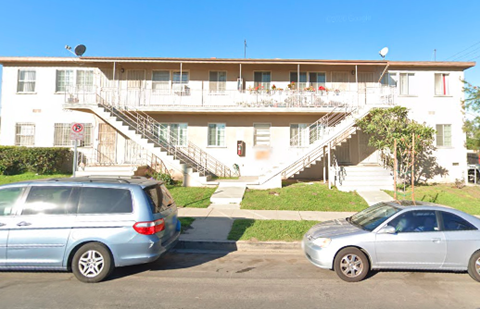 an apartment building with two cars parked in front of it