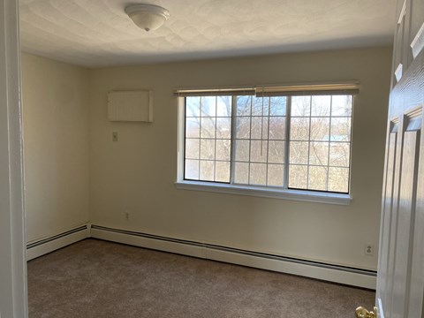 a bedroom with a large window and a carpeted floor