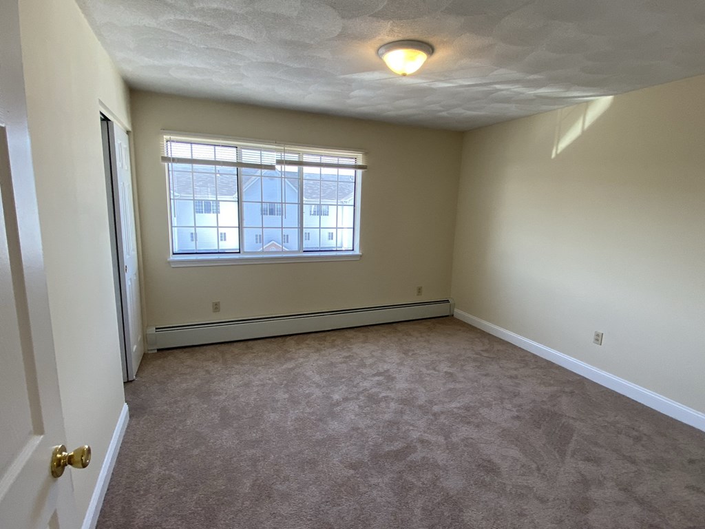 an empty living room with a window and carpet