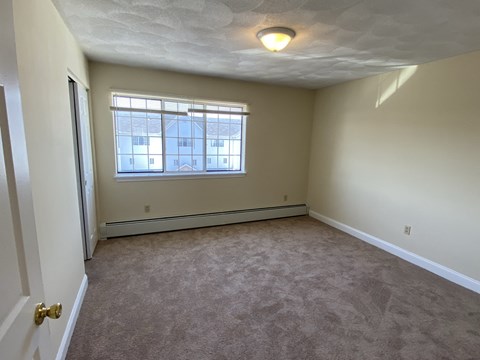 an empty living room with a window and carpet