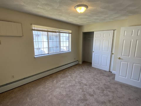 an empty bedroom with a window and two doors