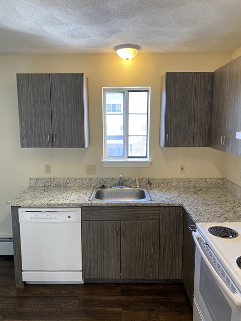 an empty kitchen with white appliances and granite counter tops