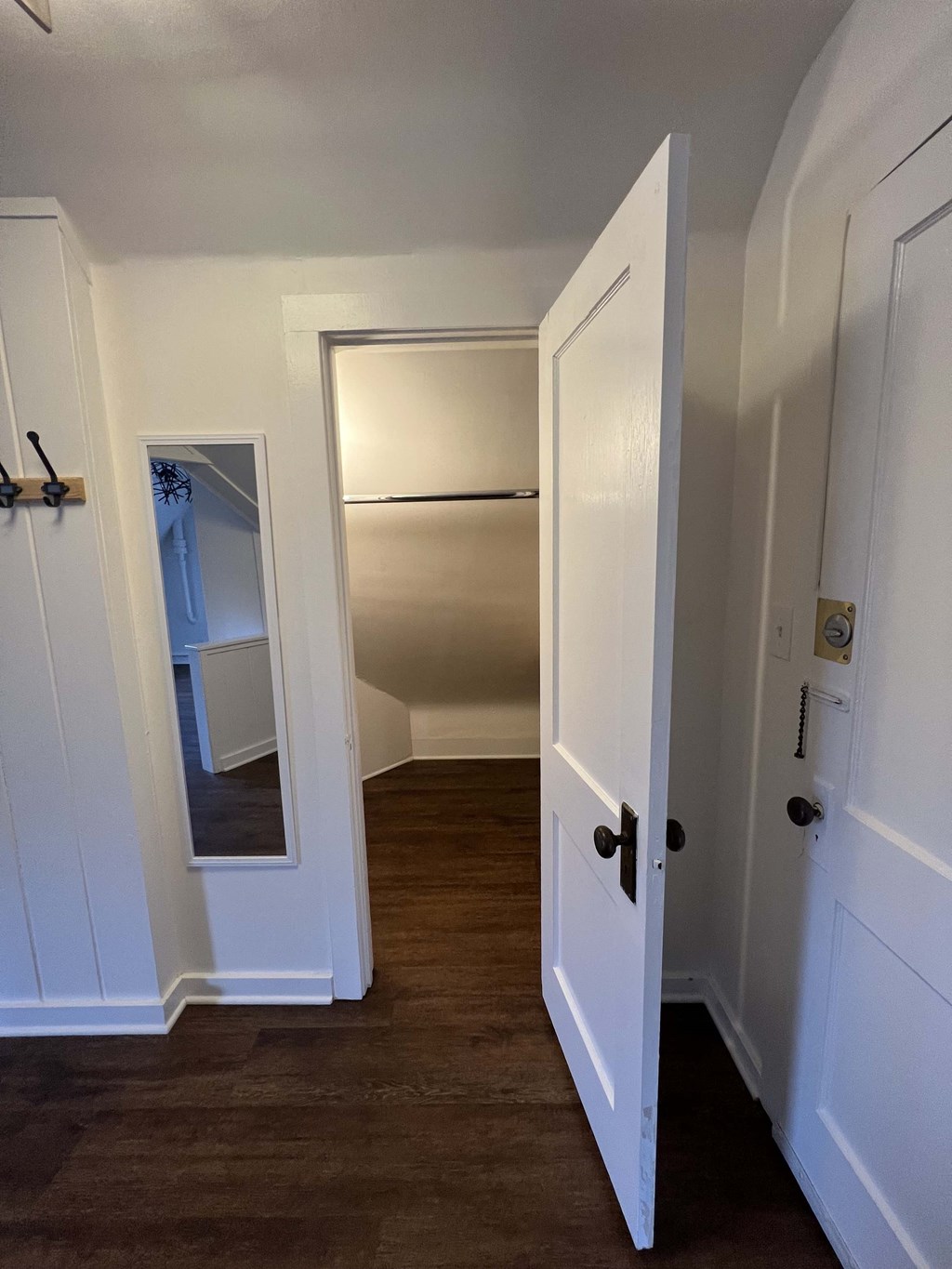 a small hallway with a door open to a closet and a mirror