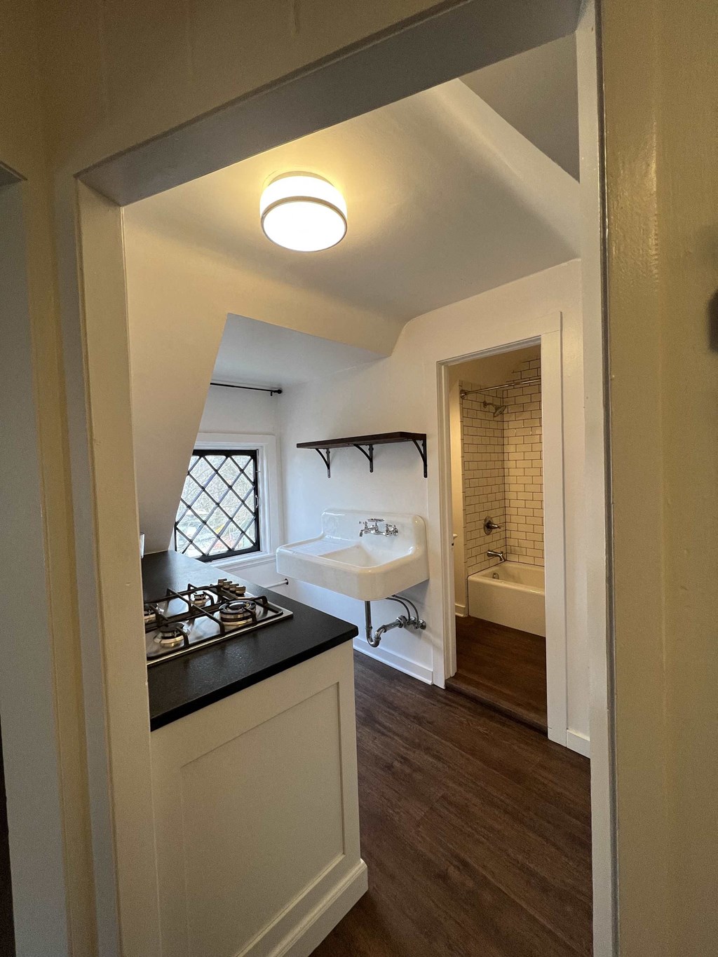 a view of the kitchen from the living room with the bathroom in the background