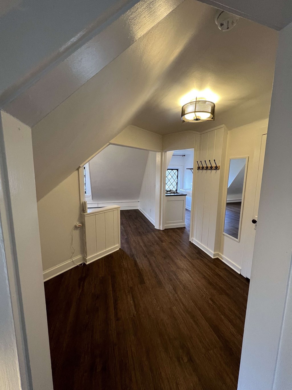 a view of a living room from the staircase with wood flooring and white walls