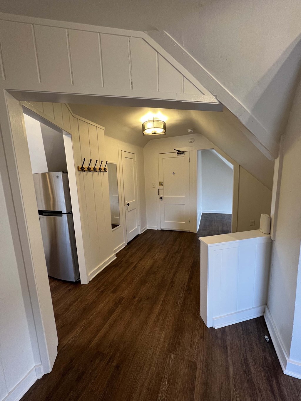 a view of a hallway with a refrigerator and a closet