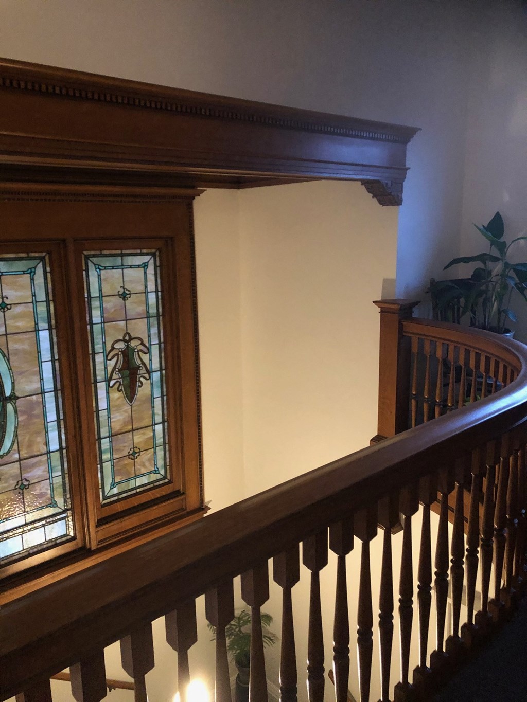 a staircase with a stained glass window and a wooden railing