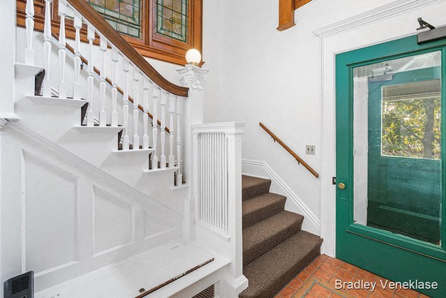 a stairway with a green door and a white staircase