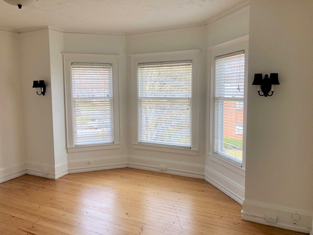 a living room with three windows and a wooden floor