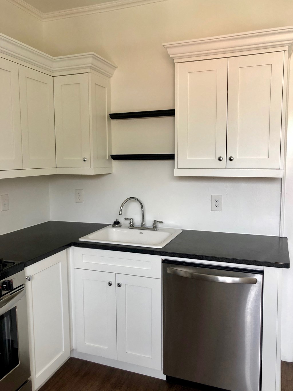 a kitchen with white cabinets and black counter top and stainless steel appliances