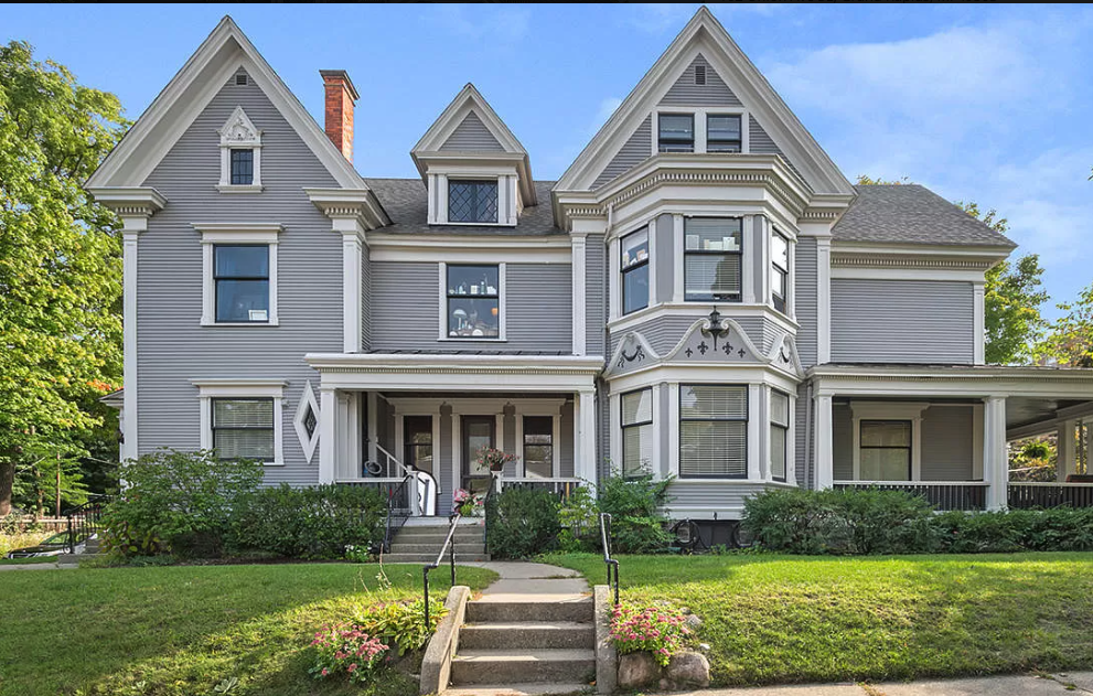 a large gray house with a yard and stairs
