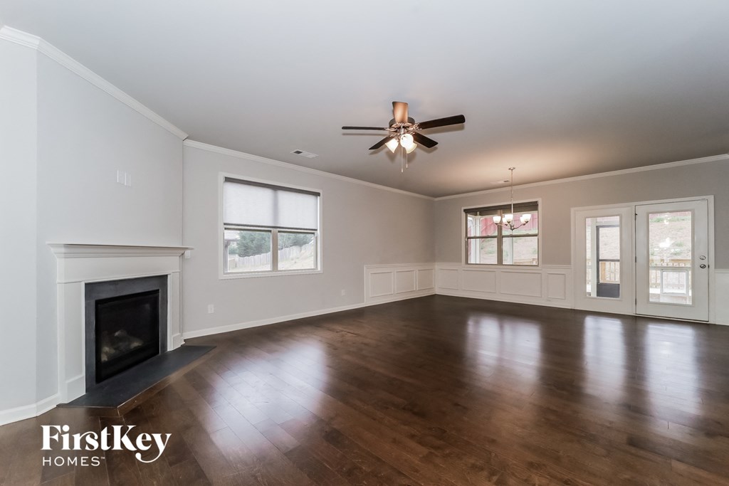 an empty living room with a fireplace and a ceiling fan
