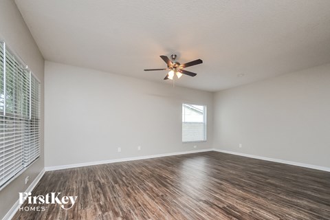 A room with a ceiling fan and wooden flooring.