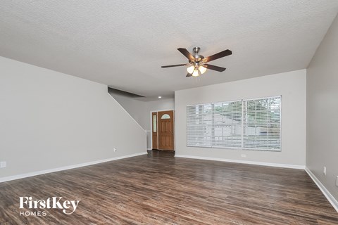 A room with a ceiling fan and wooden flooring.