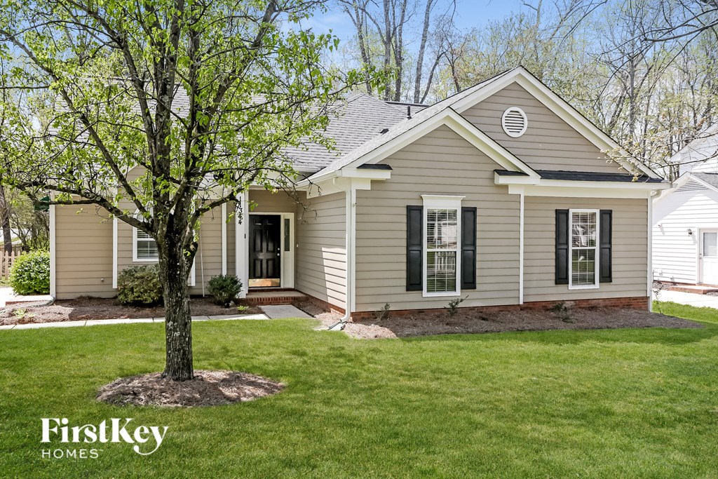 a beige house with a tree in the front yard