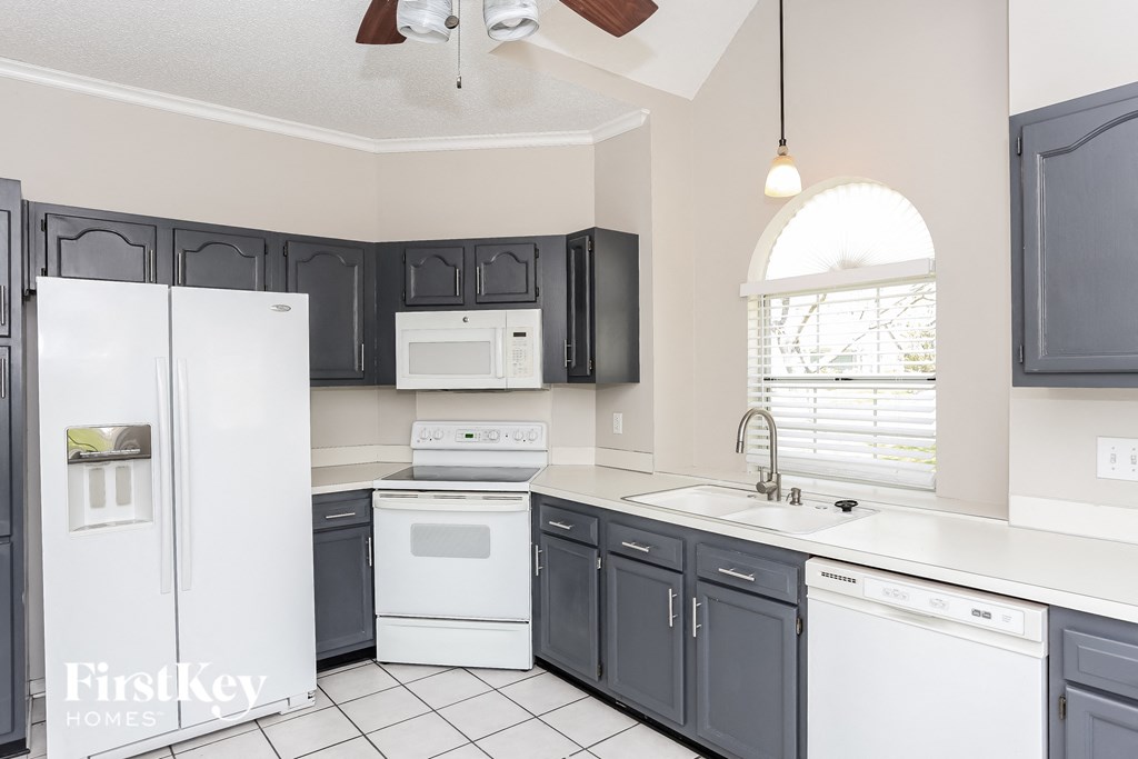 a kitchen with black cabinets and white appliances and a window