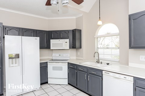 a kitchen with black cabinets and white appliances and a window