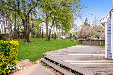 a backyard with a wooden deck and grass and trees