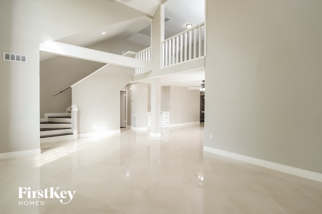 A spacious, empty room with a staircase and a balcony.