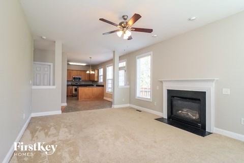 A spacious living room with a fireplace and a ceiling fan.