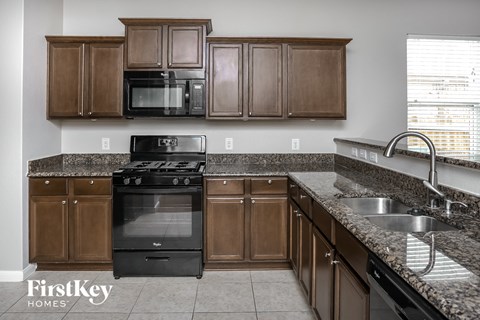 a kitchen with wooden cabinets and black appliances and granite counter tops