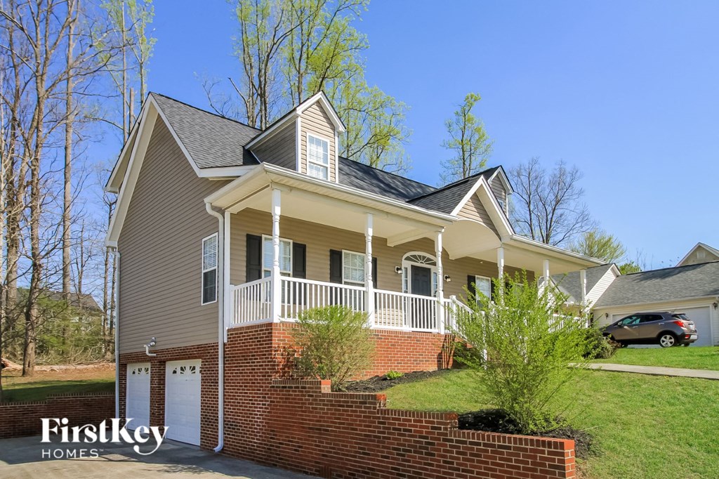 the front exterior of a house with a porch and a brick retaining wall