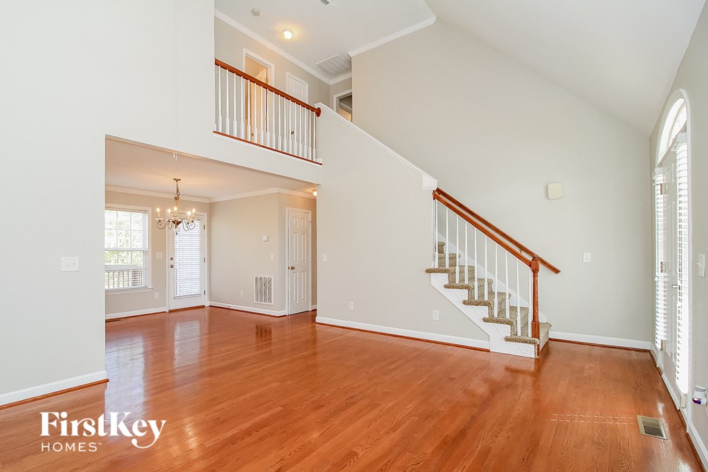 an empty living room with a staircase and wood floors