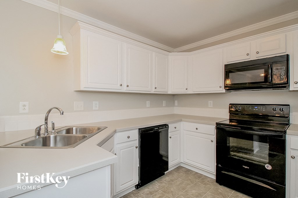 a kitchen with white cabinets and black appliances