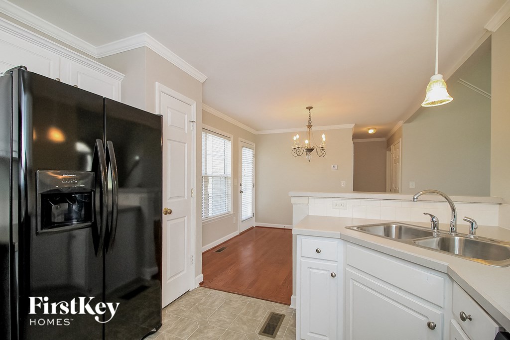 a kitchen with white cabinets and a black refrigerator