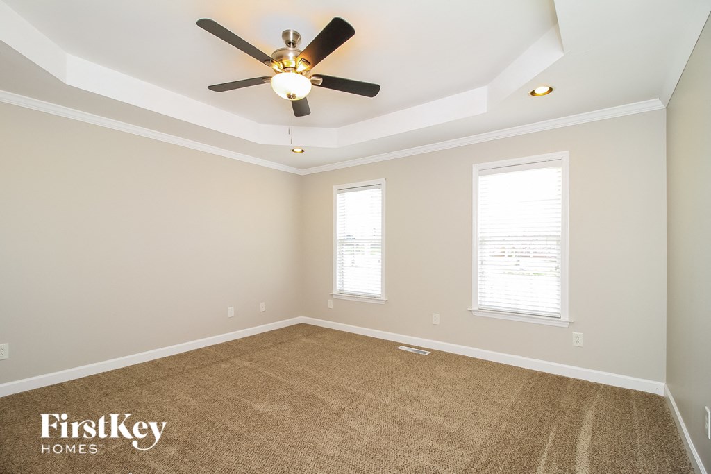 a empty room with a ceiling fan and two windows
