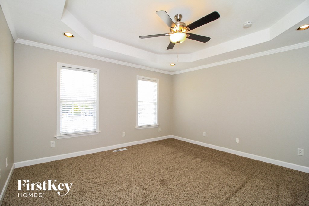 an empty room with a ceiling fan and two windows