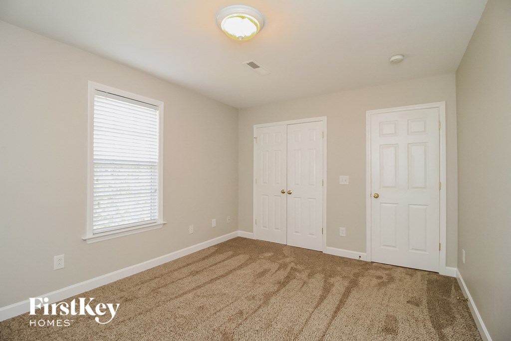 a bedroom with two closets and a carpeted floor and two doors